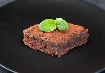 Chocolate brownie cake on a plate, black background