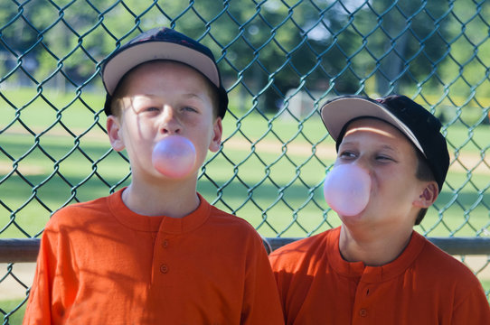 Two Young Male Baseball Players Blowing Bubbles With Bubblegum