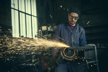 Welder cutting iron in workshop