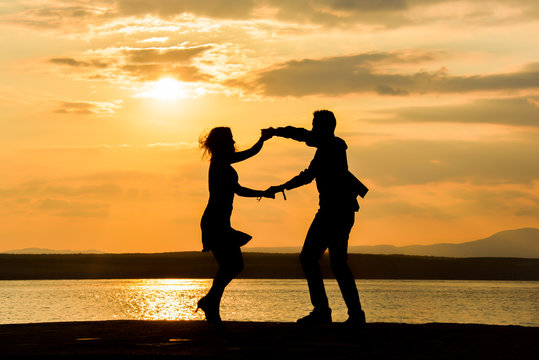 A couple dancing salsa by the sea at sunset