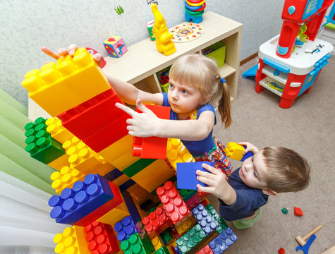 Very serious little boy and girl build big block tower 