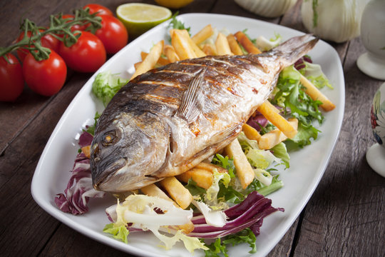 Grilled fish with french fries and salad
