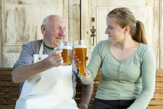 Senior man and young woman toasting with beer