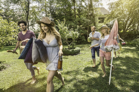 Friends walking in garden preparing for picnic