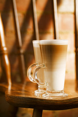 latte coffee in tall glasses on vintage chair with old brick wal