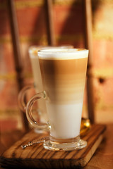 latte coffee in tall glasses on vintage chair with old brick wal