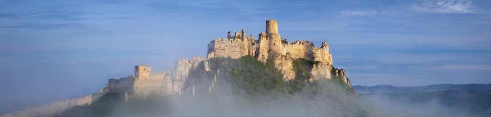 panorama with foggy old castle on the hill in the morning