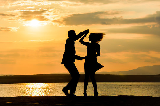 Couple silhouette dancing by the sea at sunset