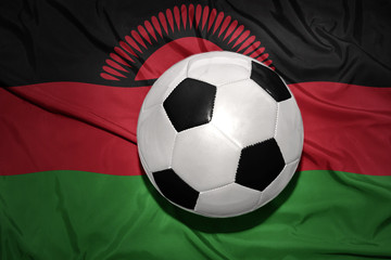 Naklejka premium black and white football ball on the national flag of malawi