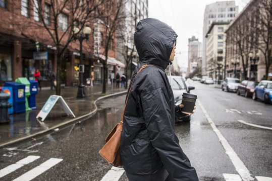 Young woman on rainy pedestrian crossing, Seattle, Washington State, USA