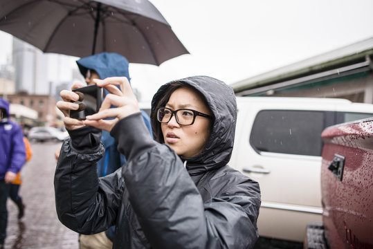 Female tourist taking smartphone photographs at Pike Place market, Seattle, Washington State, USA