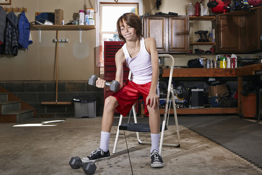 Slim Boy Struggling To Lift Hand Weight In Garage