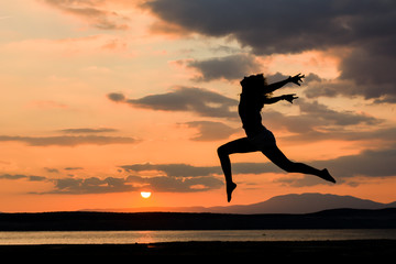 Girl jumping at sunset near the sea water