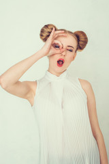 Beautiful girl with funny hairstyle. Smiling young woman making ok hand gesture.