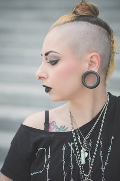 Portrait of young female punk with piercings and shaved head