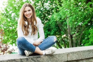 Obraz premium beautiful girl sitting outdoors in park and smiling