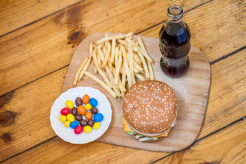 Fast food set big hamburger and french fries on wood background