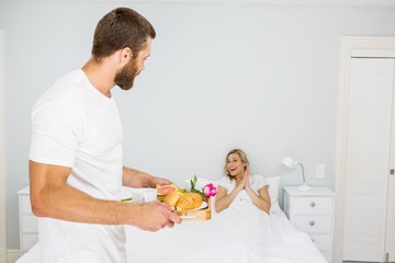 Man carrying breakfast for a woman in bed