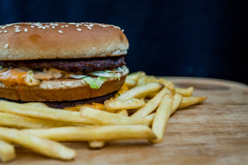 Fast food set big hamburger and french fries on wood background