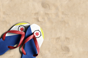 Thongs with flag of Bonaire, on beach sand