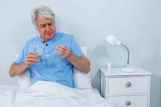 Senior man taking pills at home
