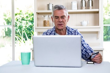 Senior man shopping online using laptop - Powered by Adobe