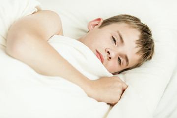 Obraz na płótnie Canvas Close up of tired boy in bed