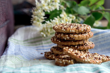 Homemade cookies with sesame and sunflower nuts on table. Cherry flowers on background