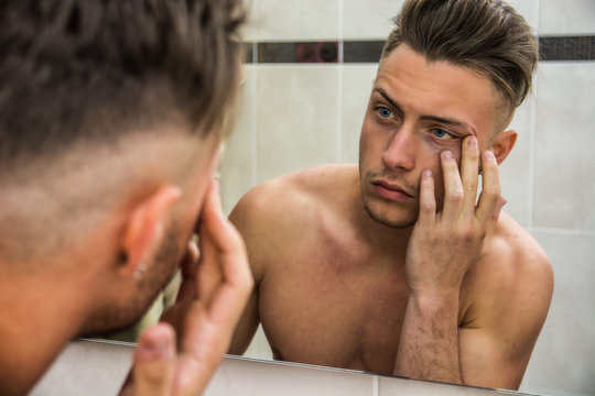 Young Man Touching His Face While Looking In Mirror