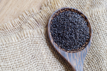 Sweet basil seeds in wooden spoon on burlap and wood background