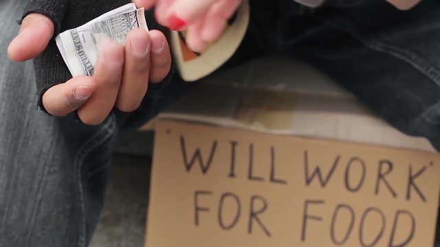 Miserable man sitting on the street and asking for alms with trembling hand