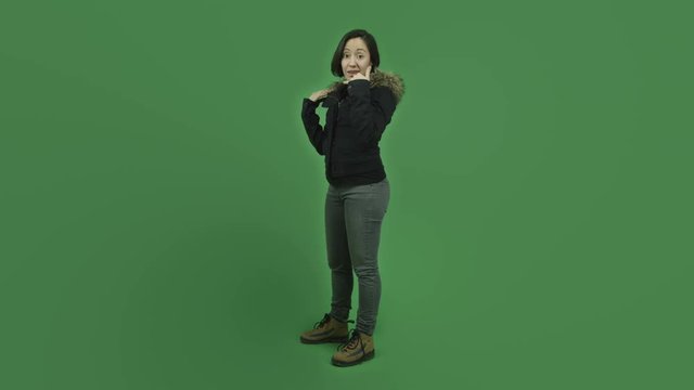 caucasian girl with winter jacket isolated on green screen with call me hand sign