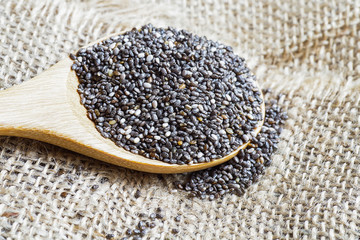 Chia seeds, super food, in wooden spoon on burlap background
