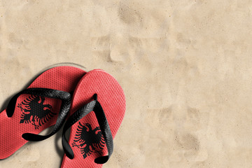 Thongs with flag of Albania, on beach sand