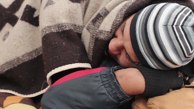 Homeless man sleeping on a bench, frozen lonely person, poverty and misery