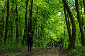 Man wearing helmet staying near the bike in the wild forest