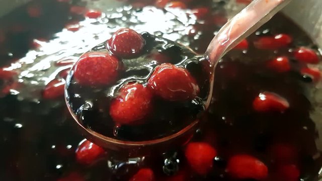 Metal scoop full of strawberry and blueberry kissel, inside a pot