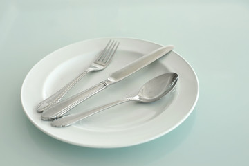 spoon fork and knife on empty white plate