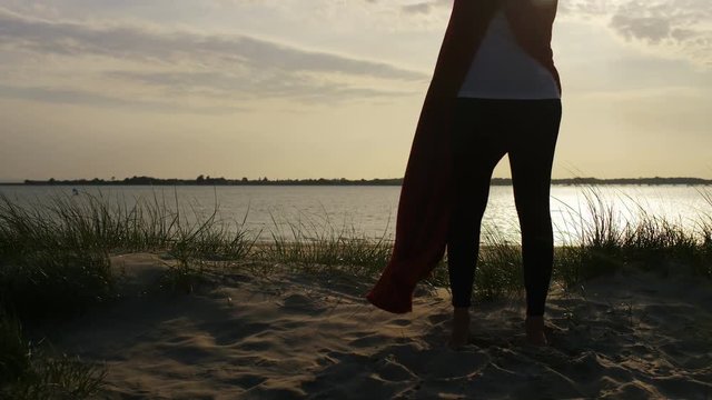 4K Young woman in a blanket stands and looks to sea, in slow motion