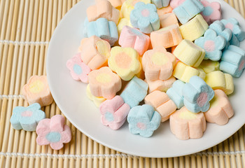 Colorful marshmallows (flower shape) on white plate