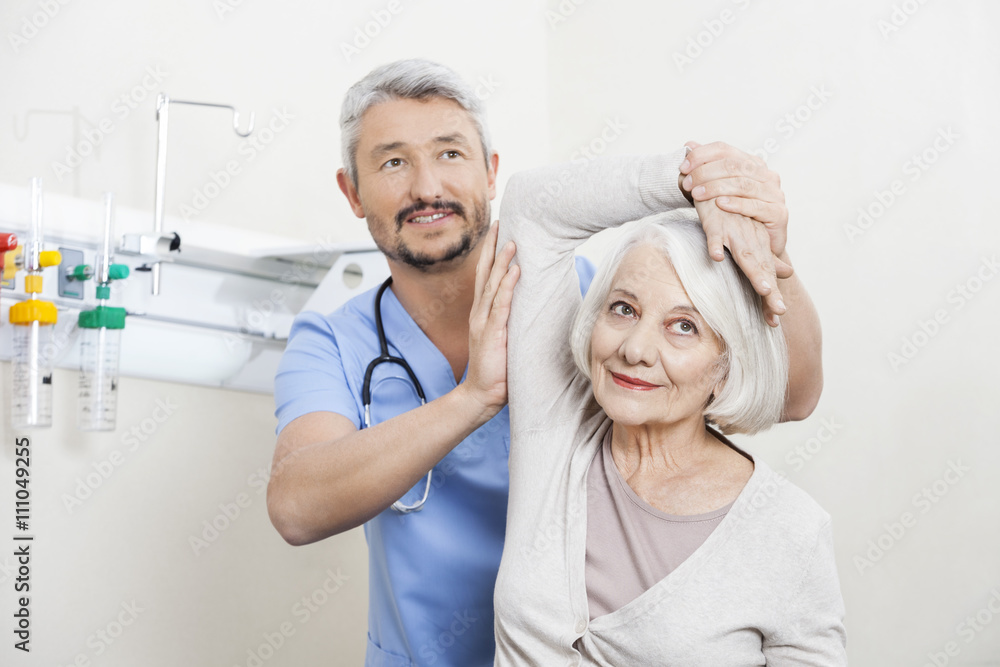 Wall mural physiotherapist helping senior patient with hand exercise