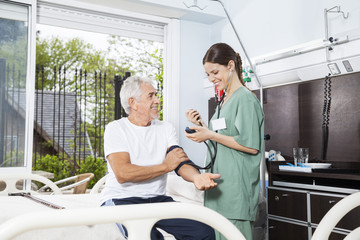 Nurse Examining Blood Pressure Of Senior Man In Rehab Center