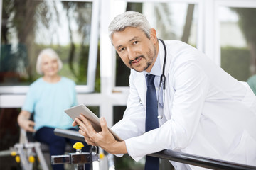 Confident Doctor Holding Digital Tablet While Leaning On Bar