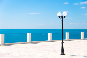 Street lamp on the sea promenade on clear sunny day - obrazy, fototapety, plakaty