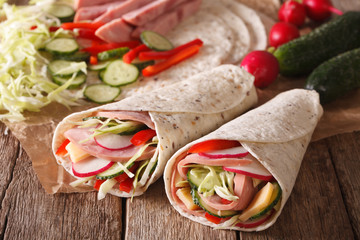 Sandwich roll filled with ham, cheese and fresh vegetables close-up. horizontal
