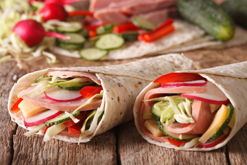 Tortilla Roll with ham and vegetables close-up and ingredients. horizontal
