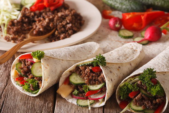 Tortilla rolls with minced meat, vegetables and ingredients close-up. horizontal

