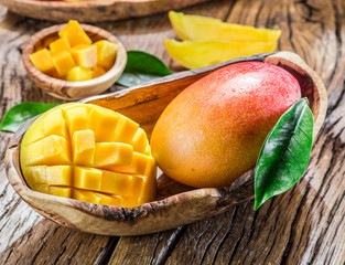 Mango fruit and mango cubes on the wooden table.