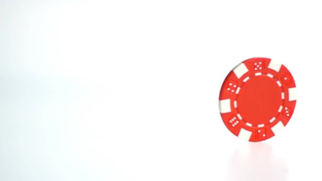red poker chip turning on white surface close up in slow motion
