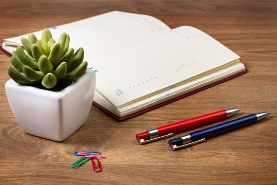 Agenda y bolígrafos sobre escritorio de madera